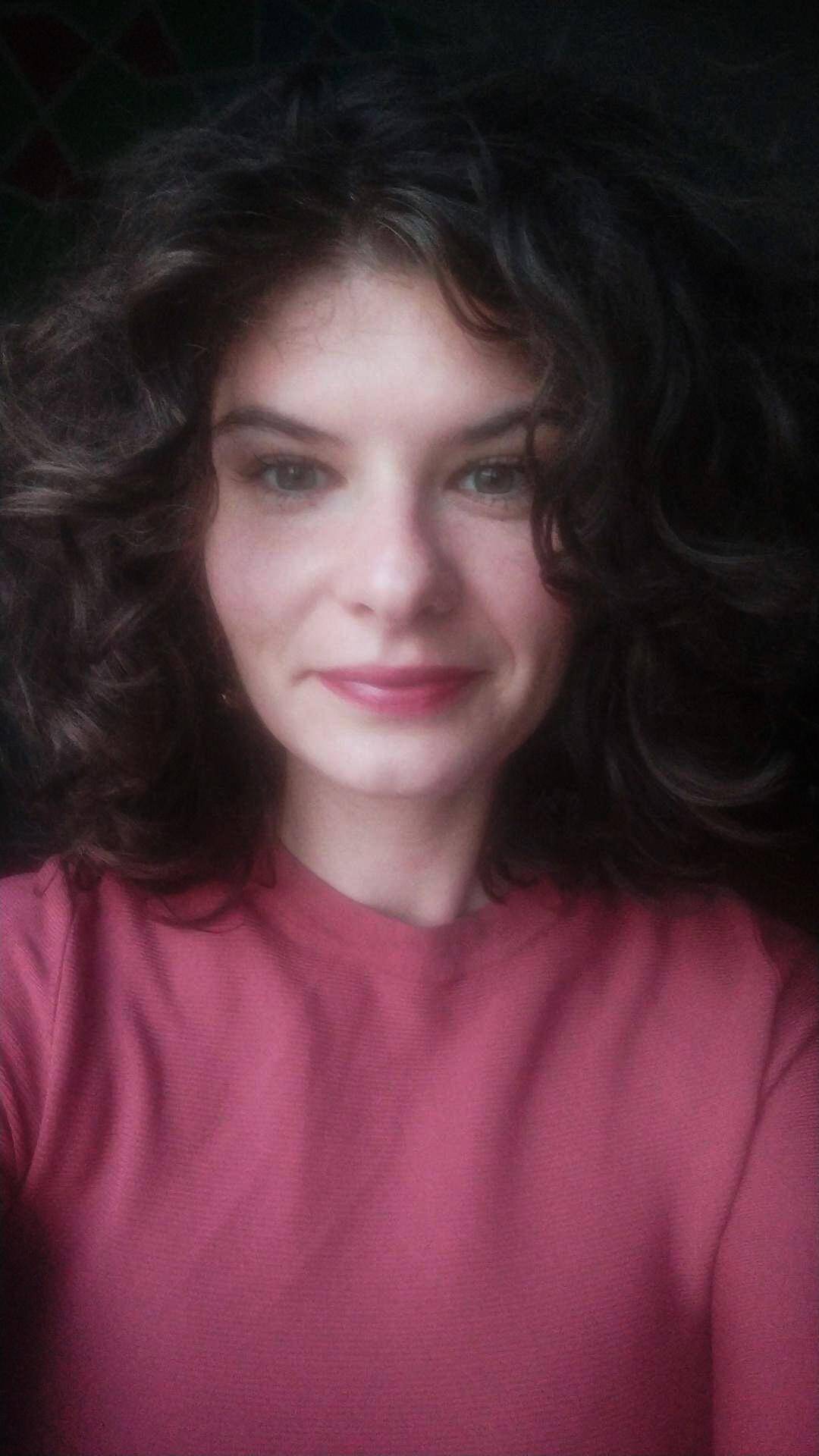 Woman with curly hair smiling, promoting mental health and self-awareness.