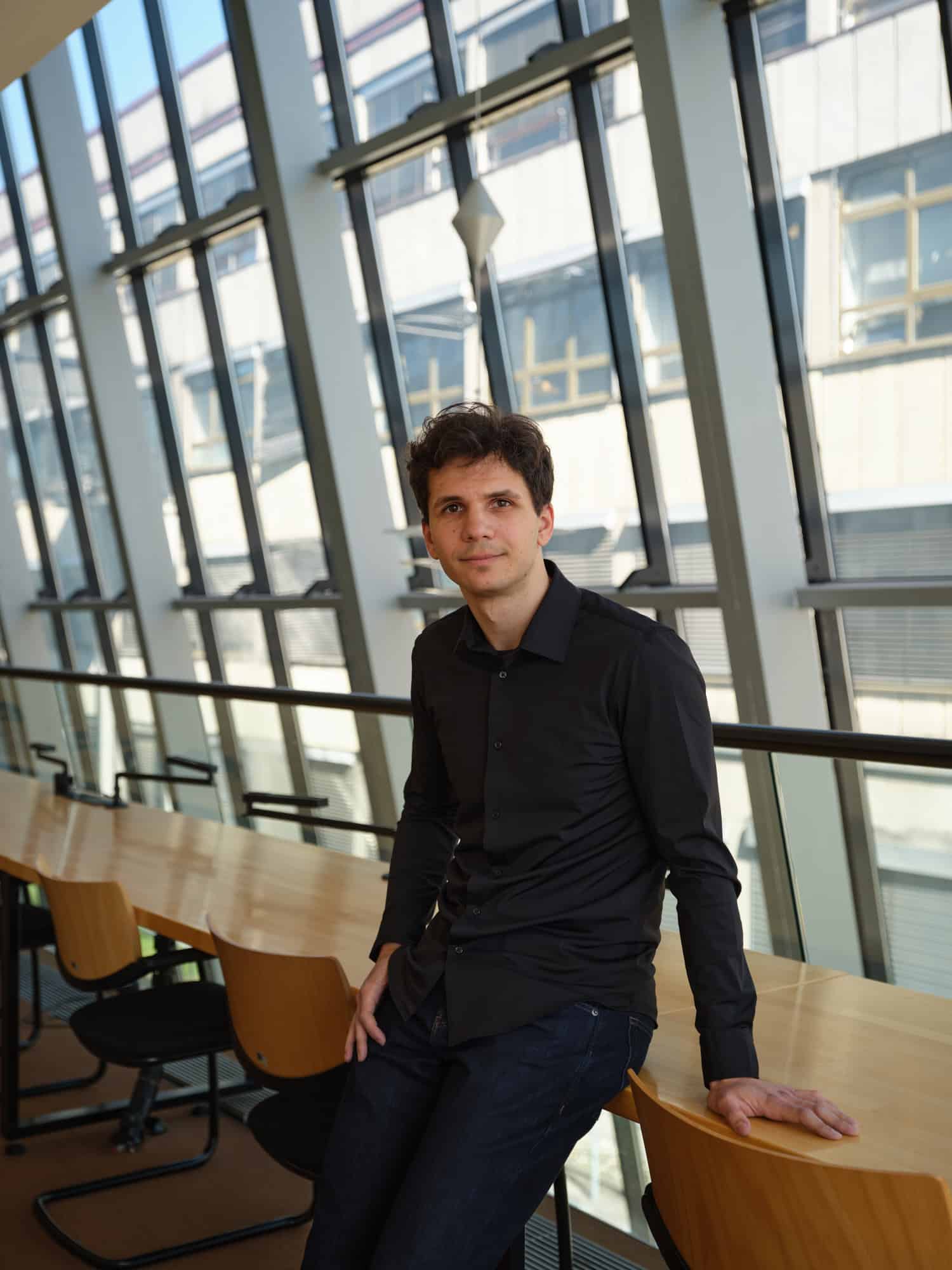 Portrait of Antun Palanović in a contemporary office setting with large glass windows.